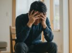頭を抱えて椅子に座っている男性